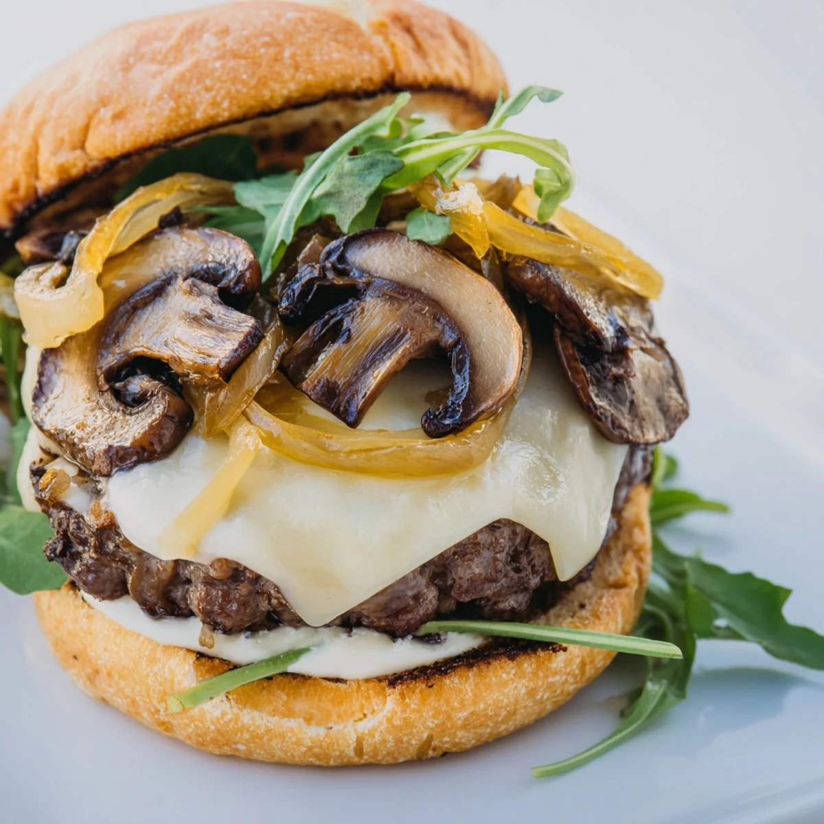Close-up of a Mushroom and Swiss Burger featuring a thick beef patty, melted Swiss cheese, and sweet caramelized onions.
