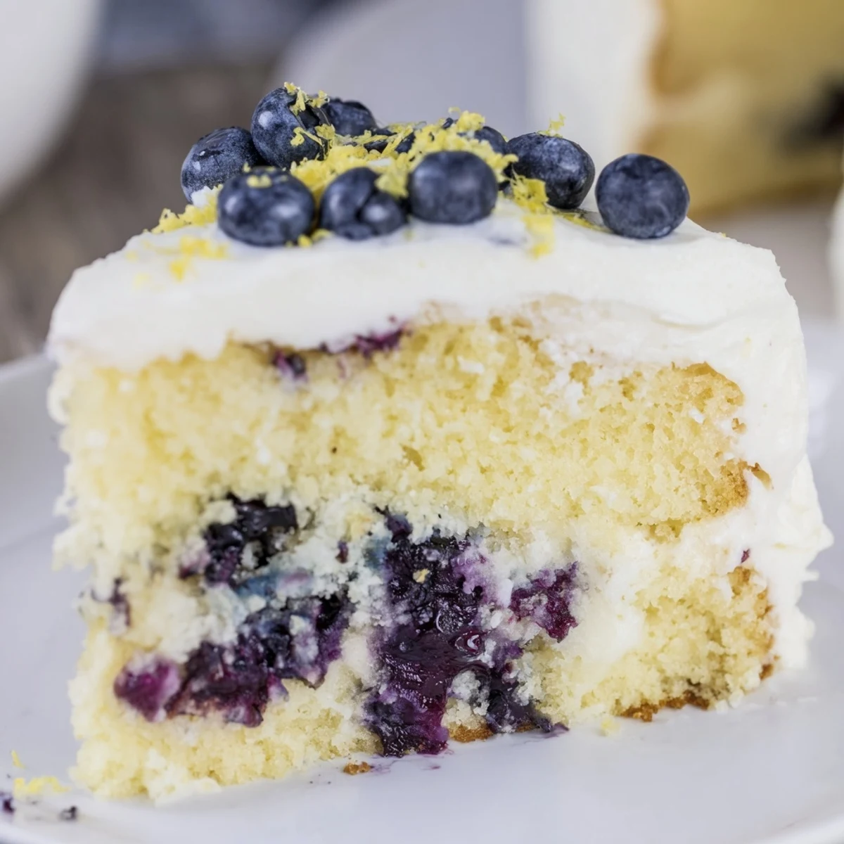 A rustic Lemon Blueberry Cake with Cream Cheese frosting features juicy blueberries baked into the tender crumb and creamy white icing.
