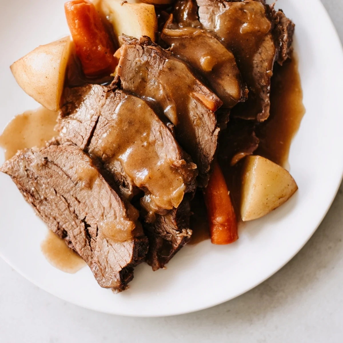 Savory Slow Cooker Pot Roast with Gravy spooned onto a white plate