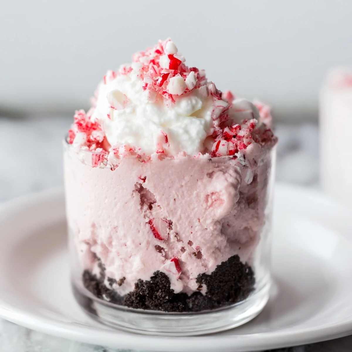 Alt text: Festive peppermint twist with candy dessert featuring smooth mousse swirled with crushed peppermint candies on a chocolate cookie crust, garnished with mint.