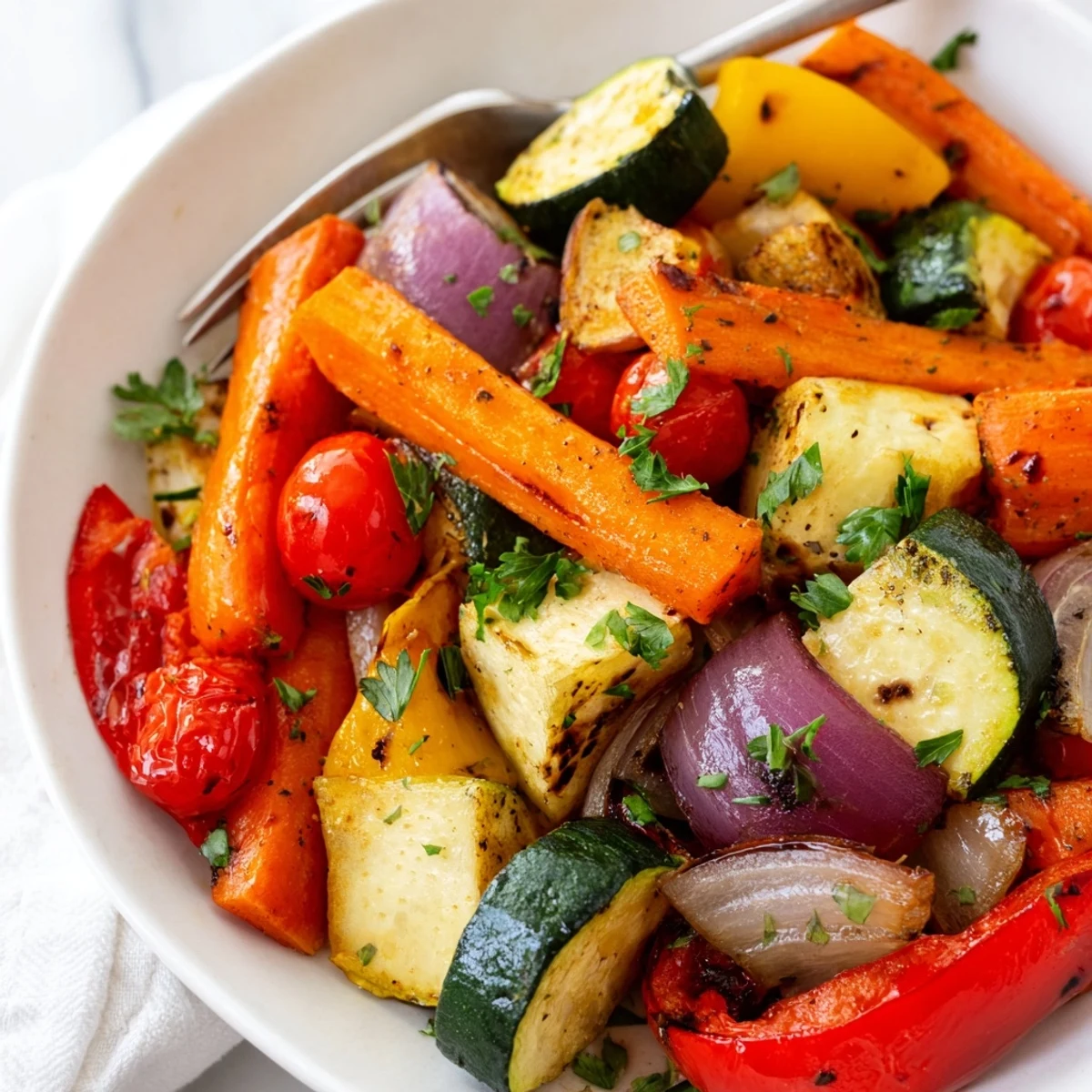 Golden roasted vegetable mix with caramelized tomatoes and onions on a rustic baking sheet.
