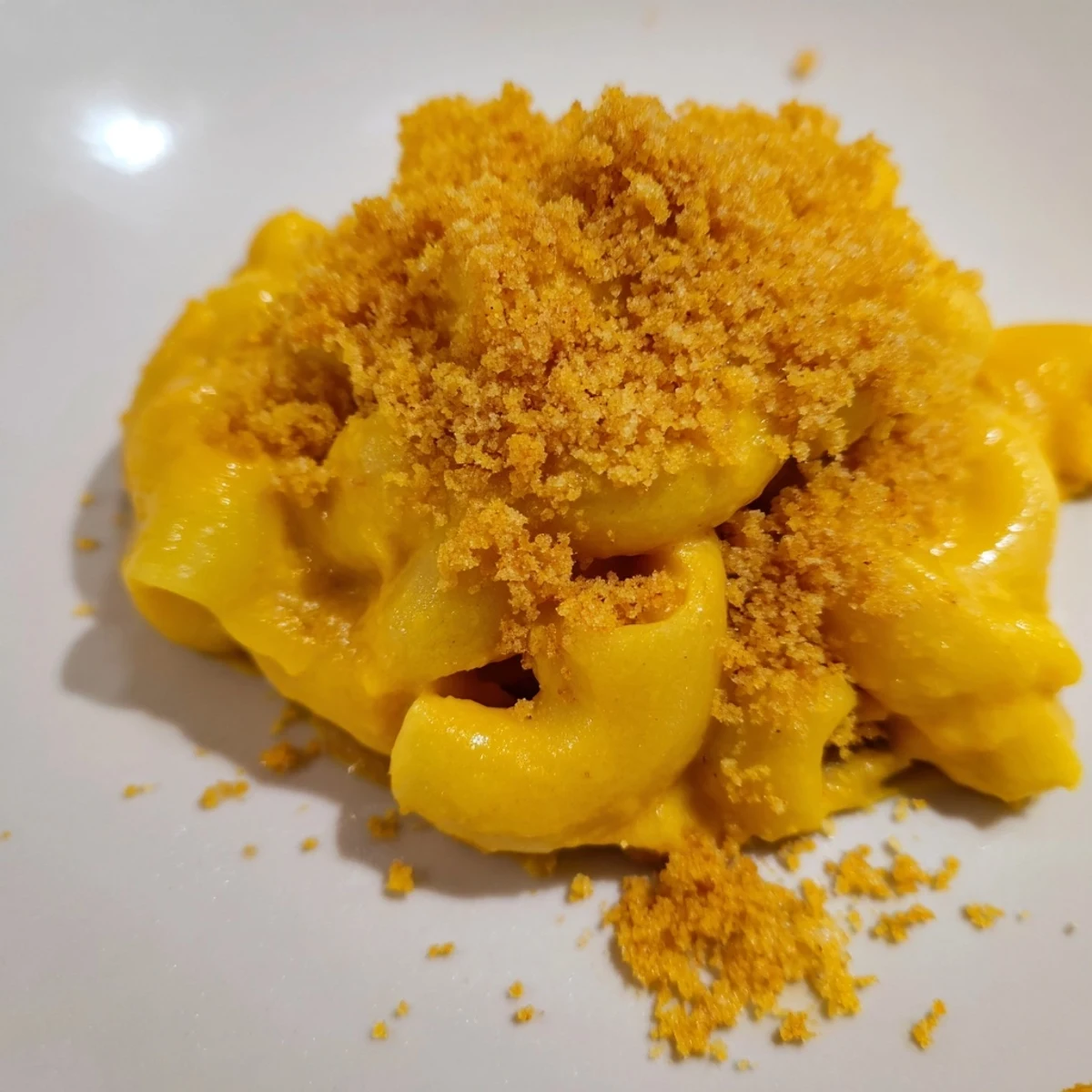 Vibrant orange roasted butternut squash sauce coats the tender elbow macaroni in a large ceramic bowl.