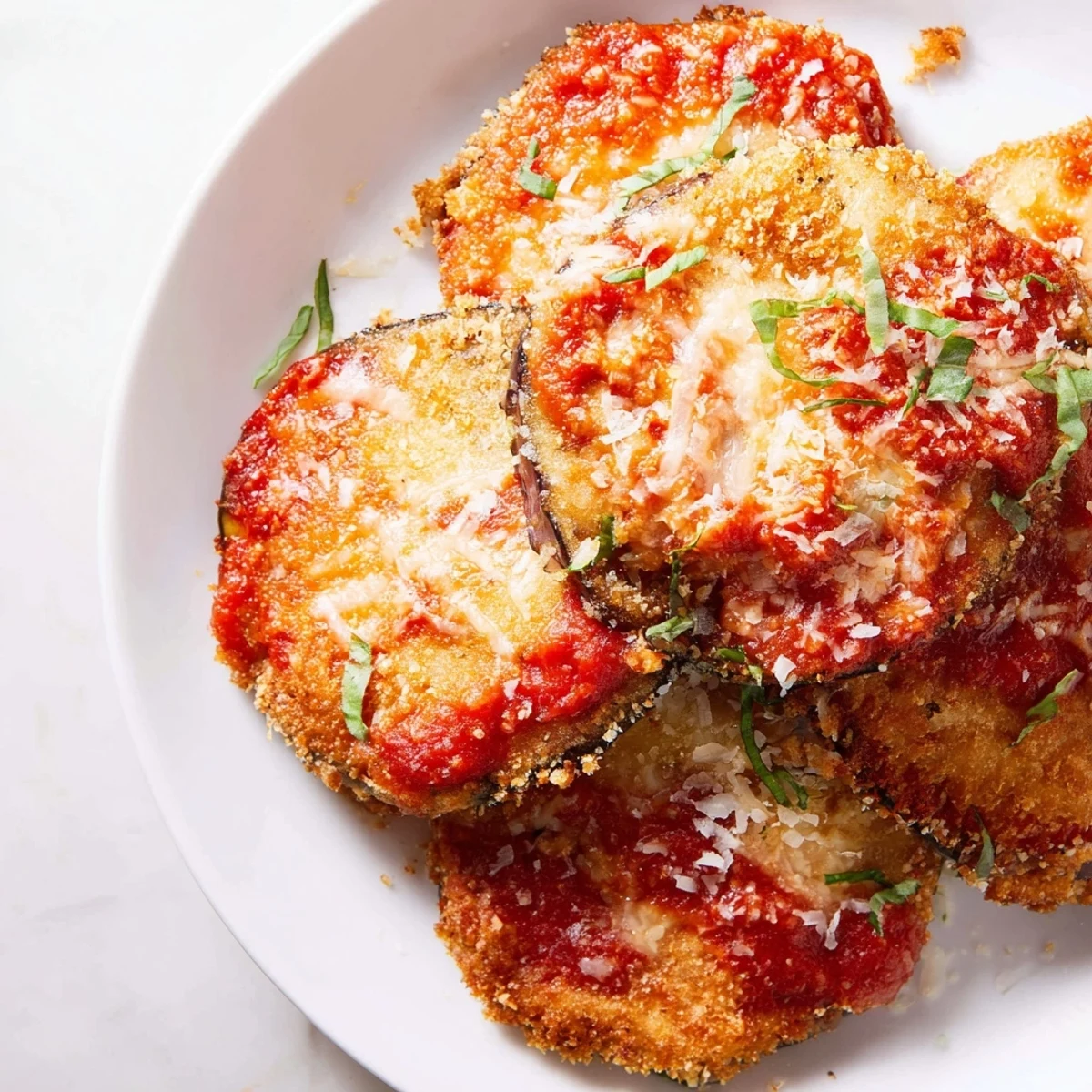 Overhead shot of freshly baked Baked Eggplant Parmesan with Marinara and Mozzarella, served with a side salad and ready to enjoy family-style.