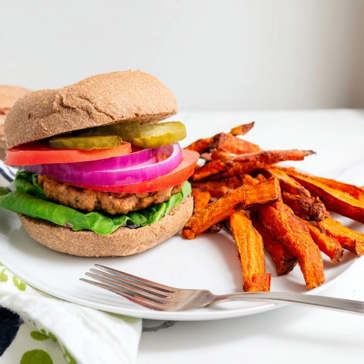 Golden-brown, juicy turkey burgers on toasted whole wheat buns, paired with crispy oven-baked sweet potato fries for a wholesome meal.  