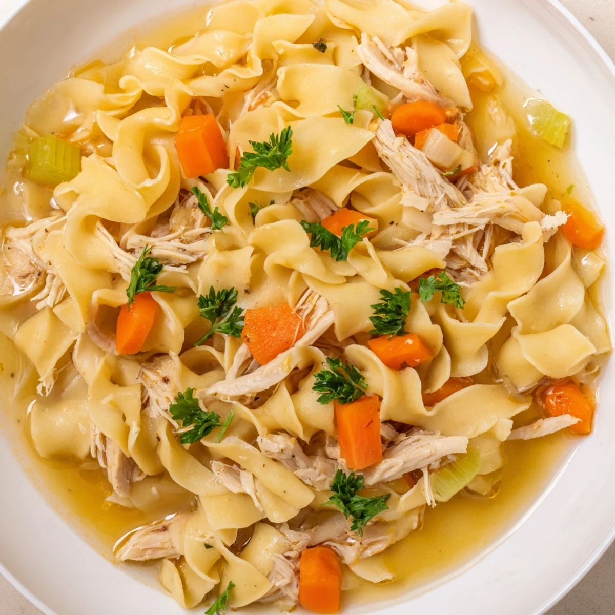 This comforting Chicken Noodle Soup with Egg Noodles highlights hearty vegetables and tender chicken pieces in a clear, steaming broth.