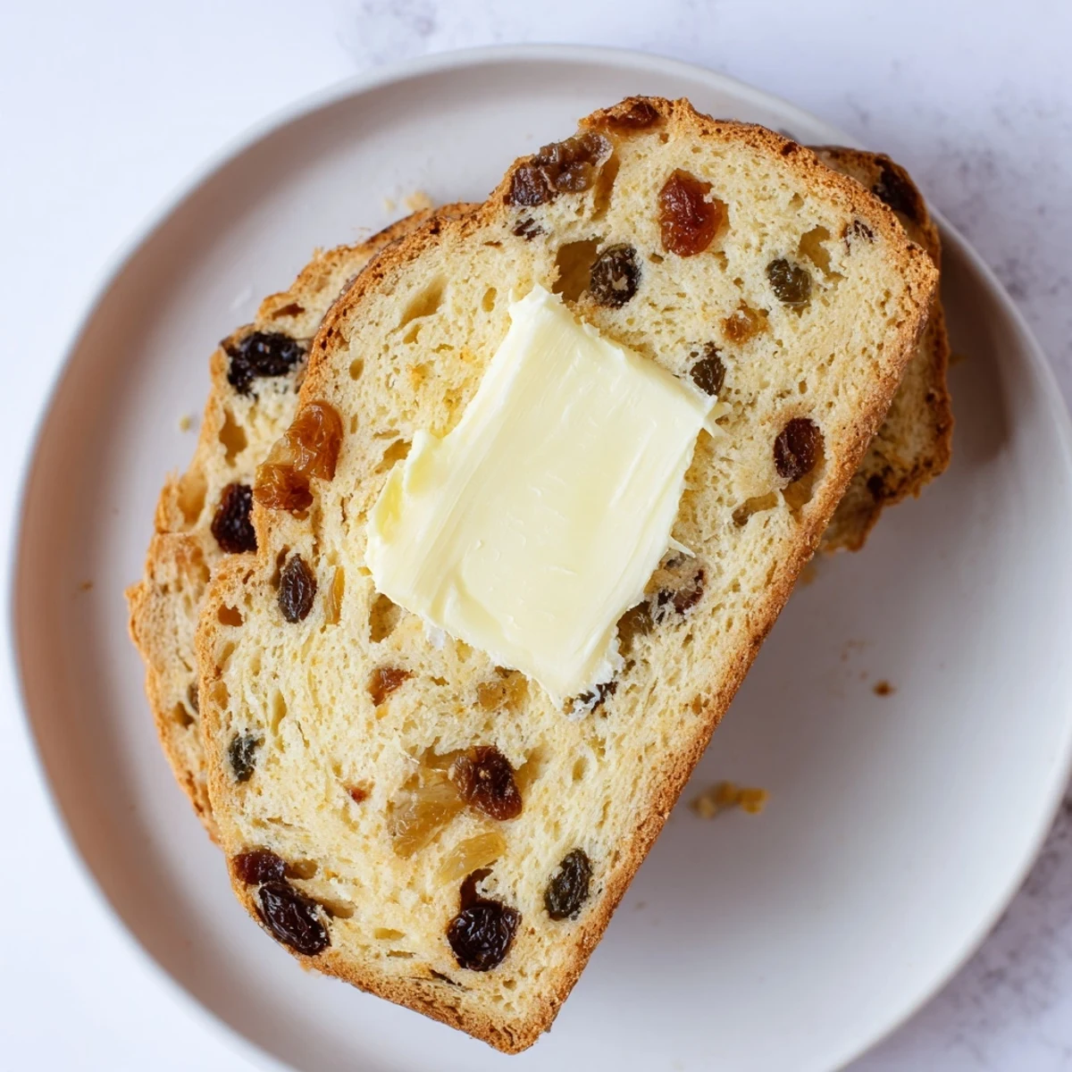 A moist slice of Irish Barmbrack with butter melting on top, ready for afternoon tea.