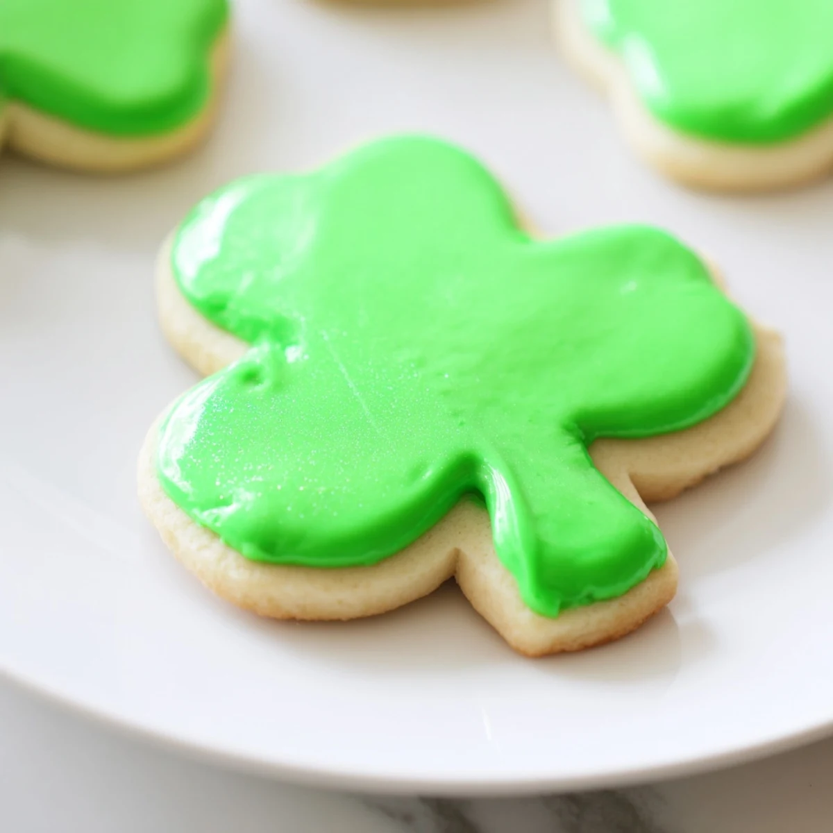 Freshly baked Shamrock Sugar Cookies with vibrant green icing and sparkling sanding sugar arranged on a cooling rack.