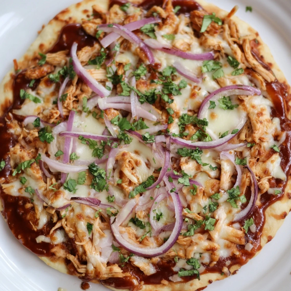 Freshly baked BBQ Chicken Pizza with Red Onion topped with melted mozzarella and smoked gouda, finished with cilantro.