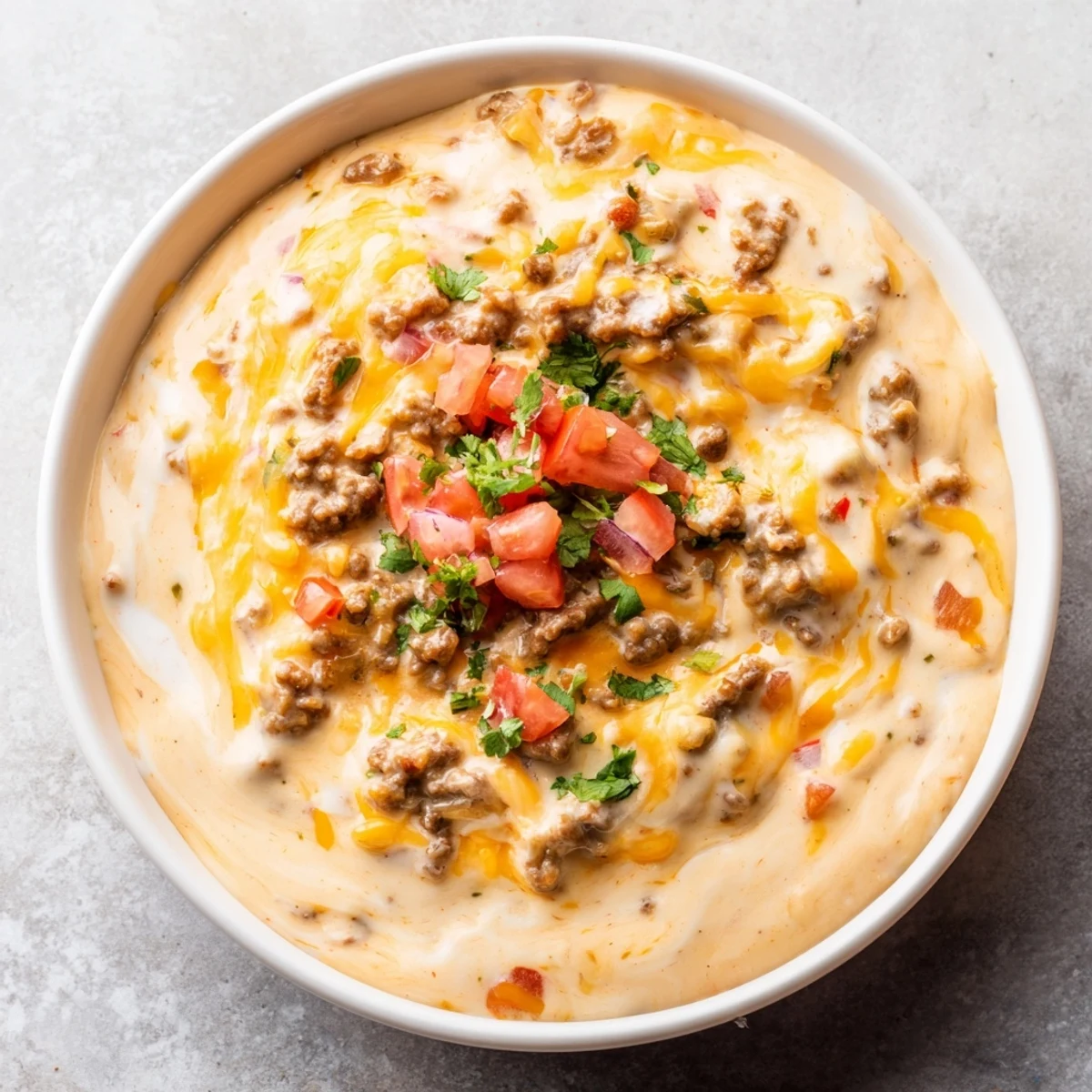 Sizzling skillet of Beef Queso Dip with seasoned ground beef and cheddar, surrounded by crunchy tortilla chips for parties.