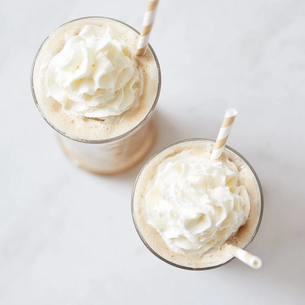 Two glasses of Starbucks Vanilla Bean Frappuccino over ice showing a smooth blended texture on a clean countertop.