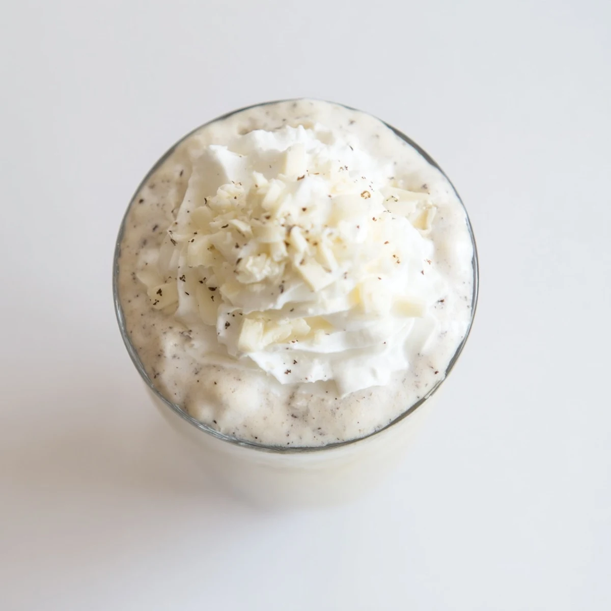 Creamy Vanilla Bean Frappuccino topped with whipped cream and white chocolate shavings in a tall glass.  