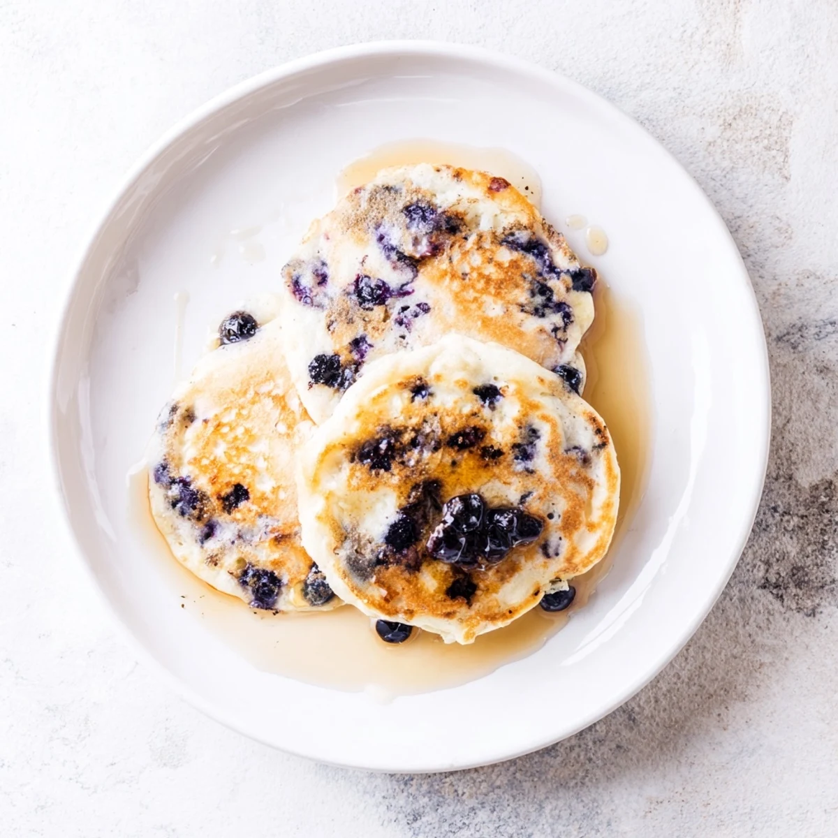 Warm Fluffy Greek Yogurt Blueberry Pancakes drizzled with maple syrup for brunch.