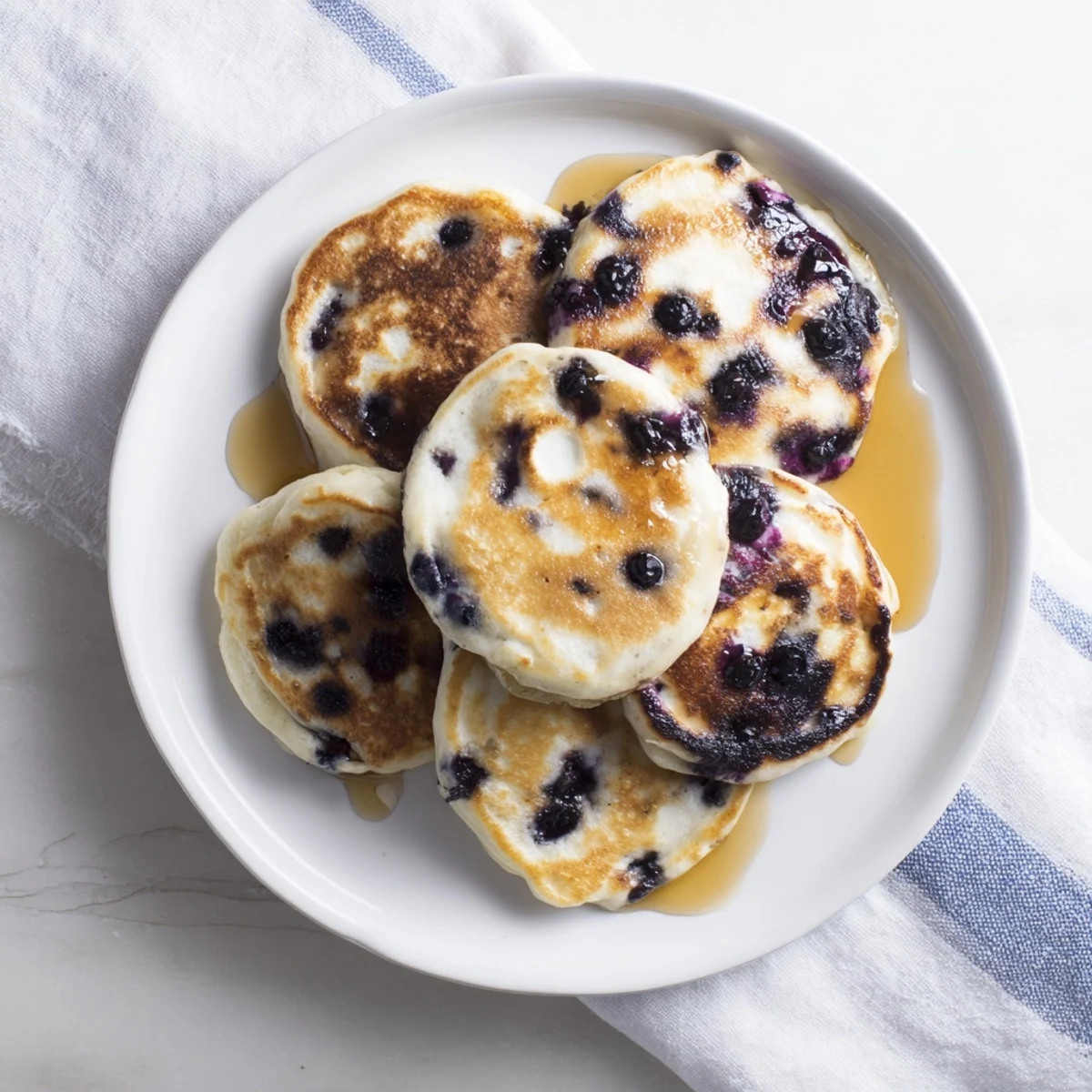 A close-up of fluffy Greek yogurt blueberry pancakes with powdered sugar dusting.