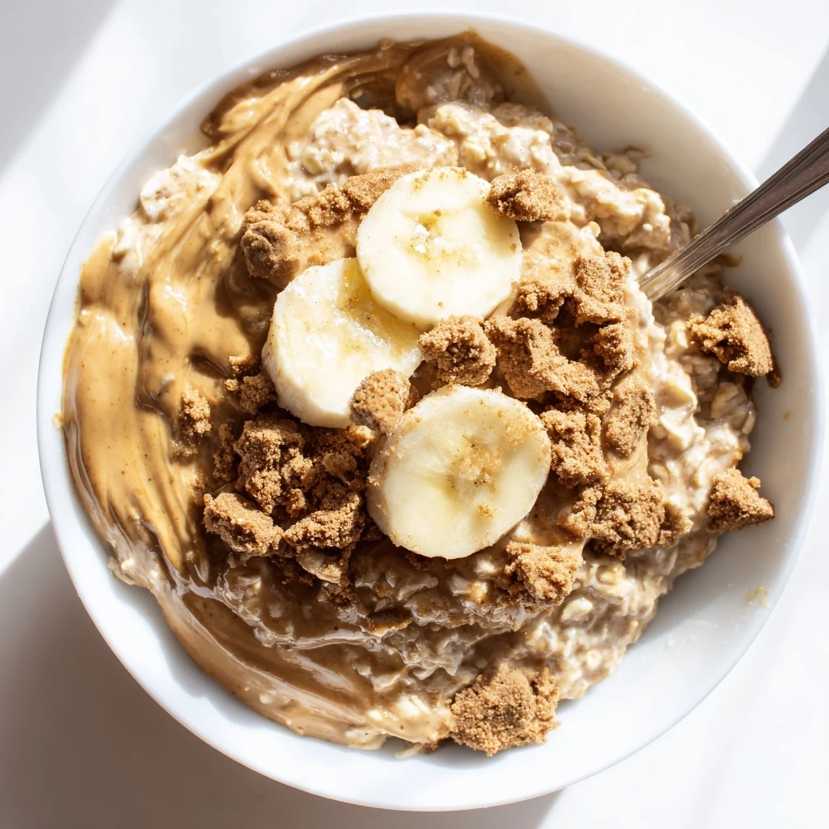 A jar of Quick Biscoff Overnight Oats layered with Greek yogurt and oats, ready to enjoy with a hot cup of coffee.