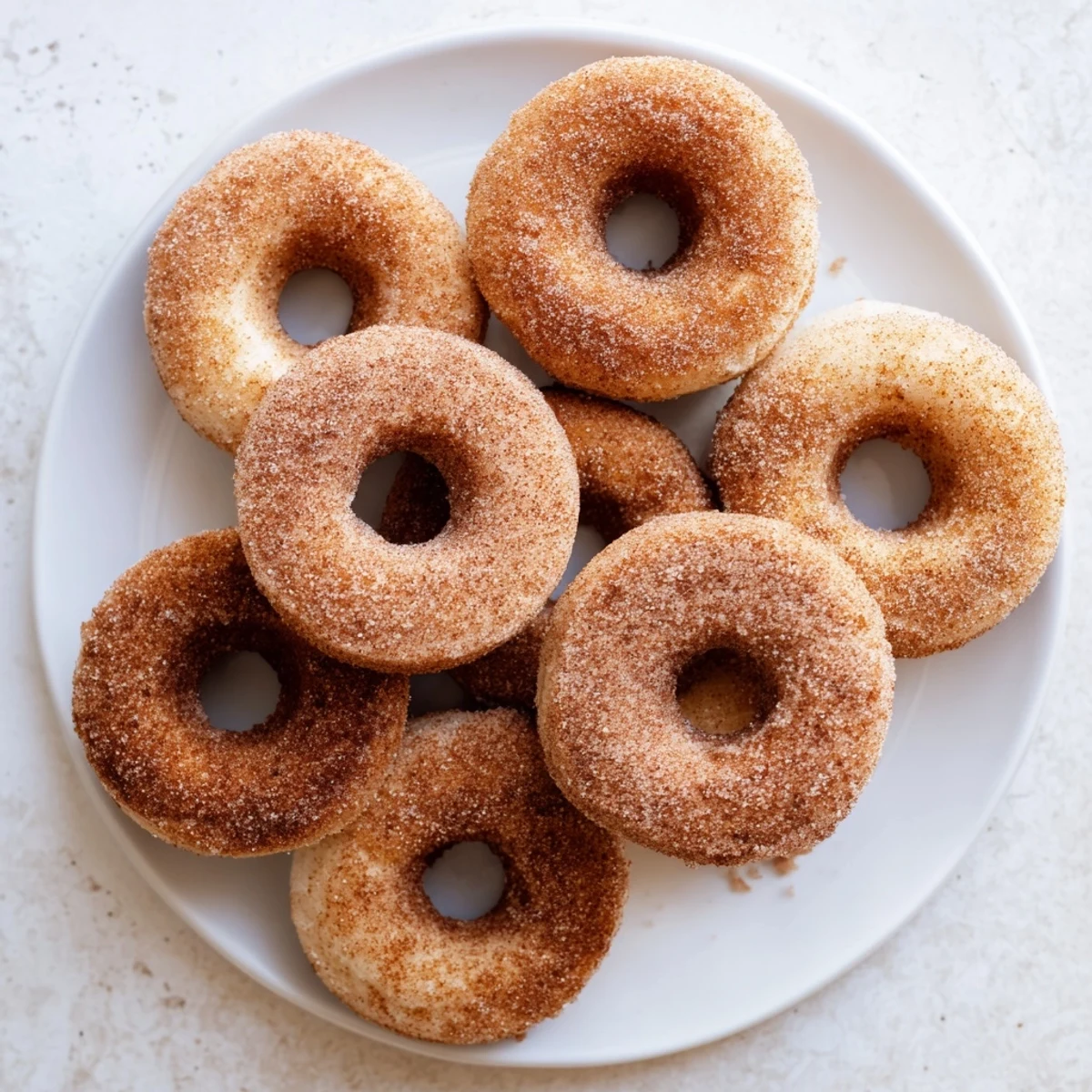 Warm, golden-brown Delicious Baked Cinnamon Sugar Donuts You Can’t Resist coated in sparkling cinnamon sugar, ready to serve as a sweet breakfast treat.
