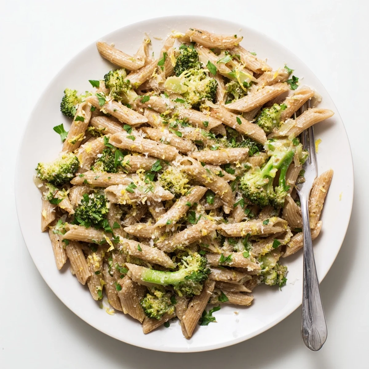 A close-up view shows steaming Easy Healthy Broccoli Pasta tossed with Parmesan and red pepper flakes on a rustic table.