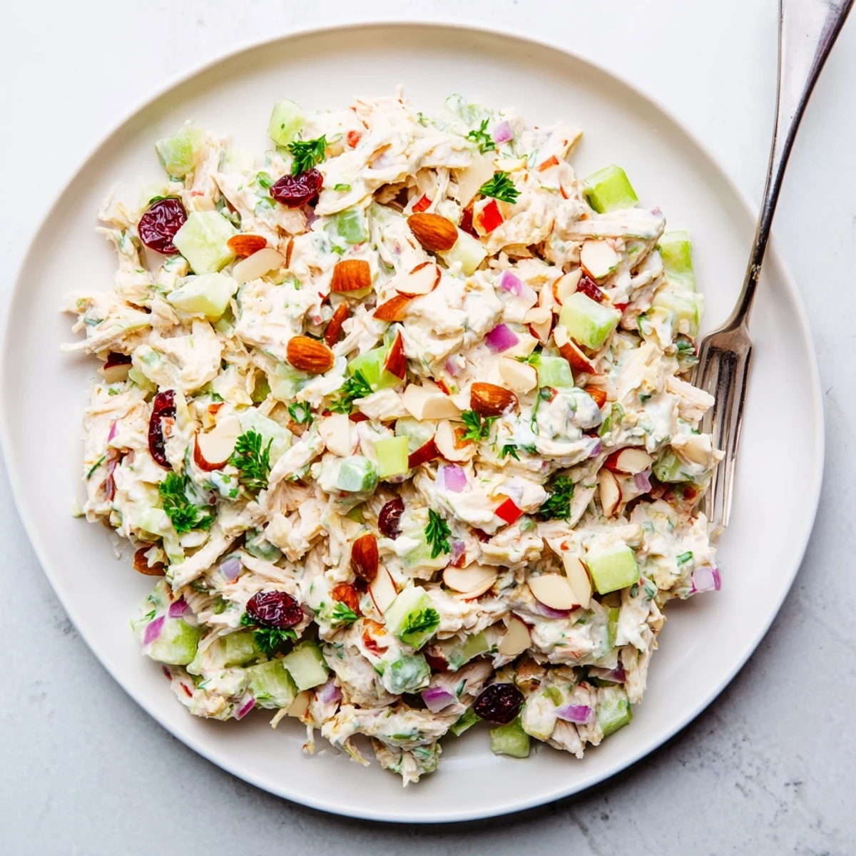 Healthy Greek yogurt rotisserie chicken salad served over greens with crunchy almonds