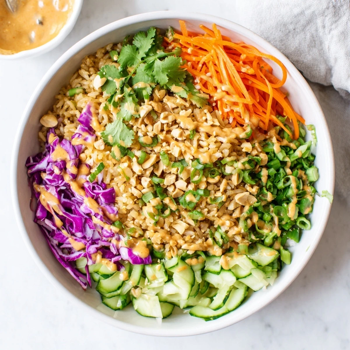 Golden fried rice salad tossed in creamy peanut sesame dressing with vibrant purple cabbage and carrots
