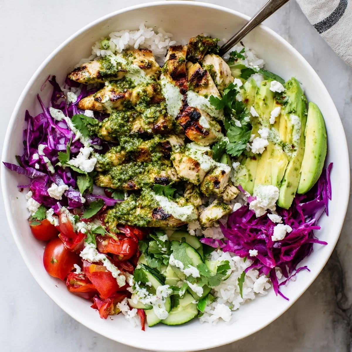 Juicy chimichurri marinated chicken breast slices arranged in a bowl with fresh avocado and crisp veggies