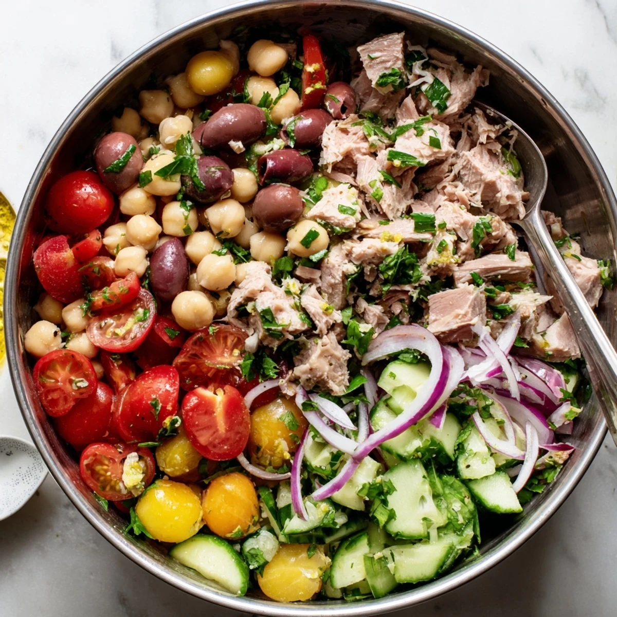 Colorful hearty tuna and garbanzo bean salad with fresh vegetables and zesty lemon dressing in a white bowl