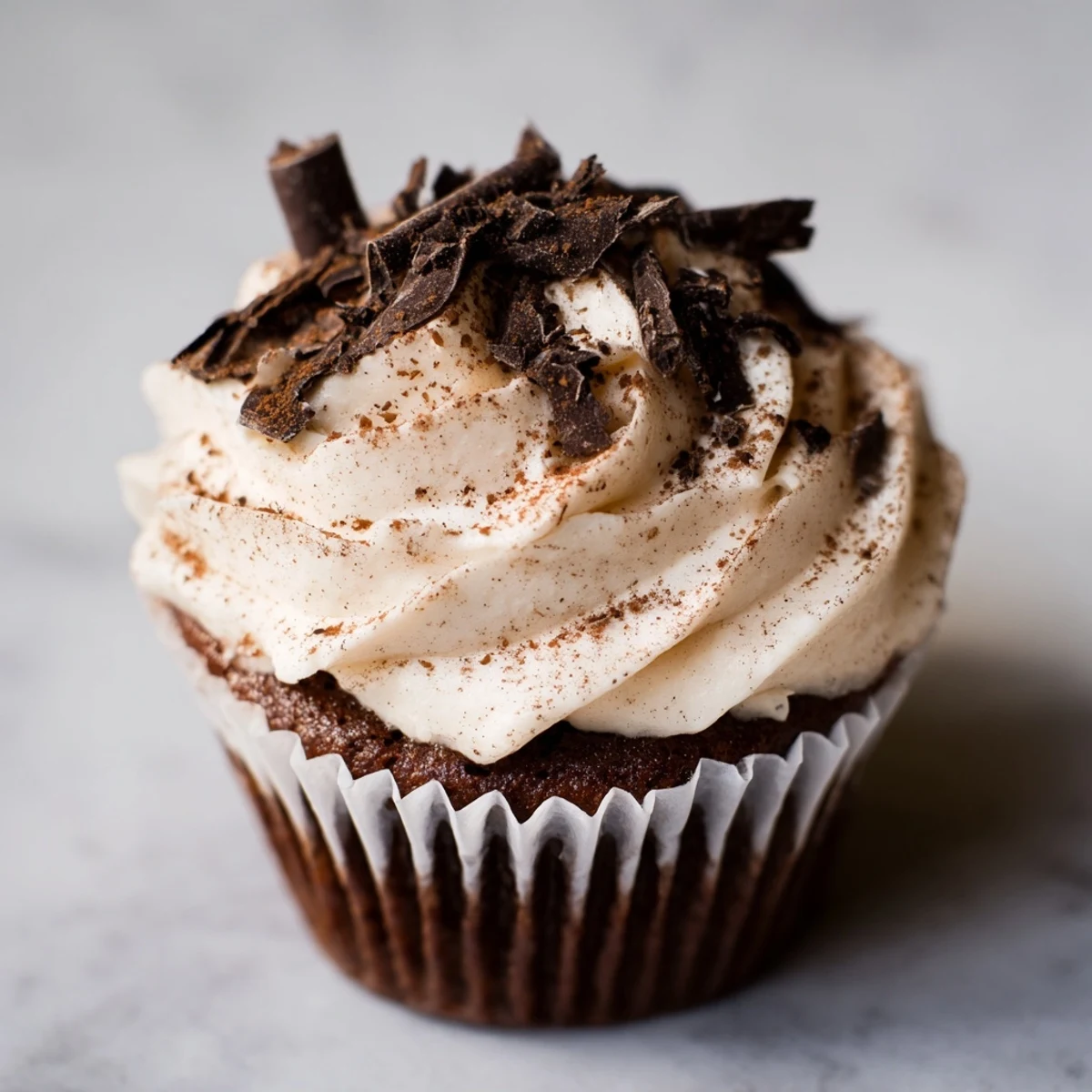 Rich chocolate cupcakes filled with coffee syrup and creamy mascarpone frosting on white plate