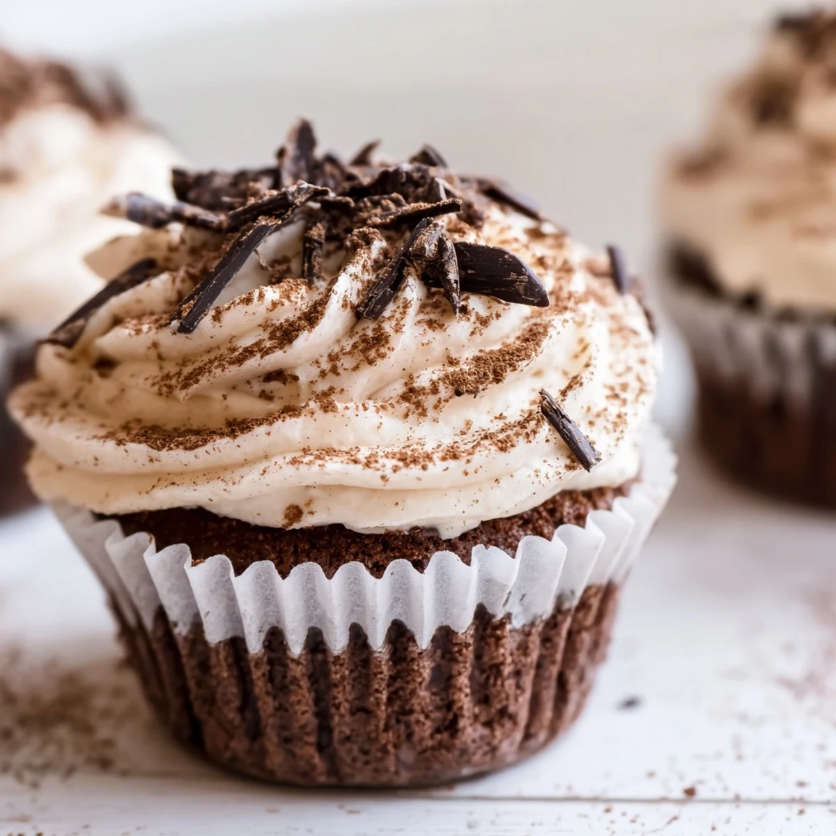 Chocolate tiramisu cupcakes garnished with dark chocolate shadows and powdered cocoa topping