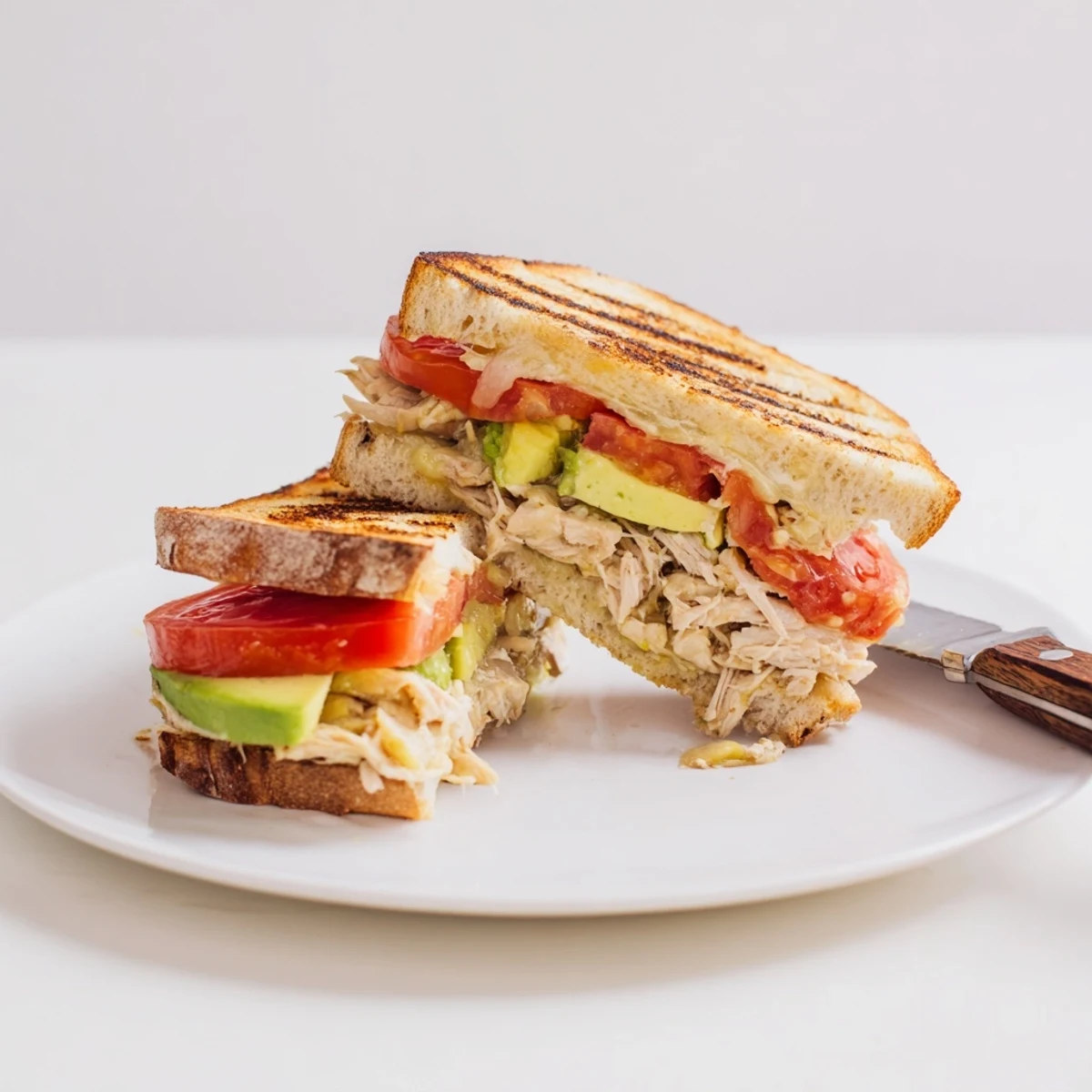 Golden brown Chicken Avocado Melt Sandwich with melted cheese oozing from toasted sourdough bread slices