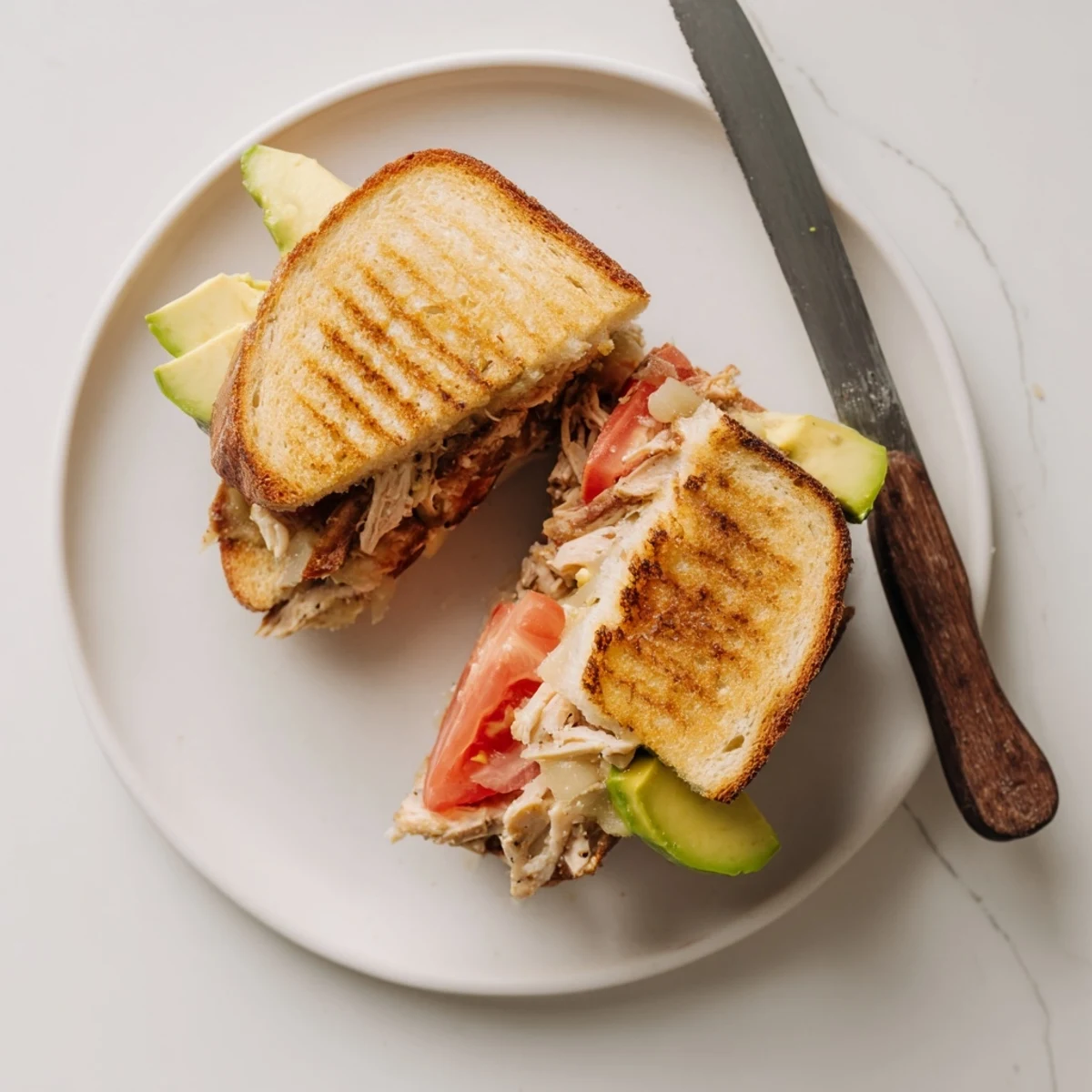 Juicy chicken and creamy avocado stacked inside a grilled Chicken Avocado Melt Sandwich cut diagonally