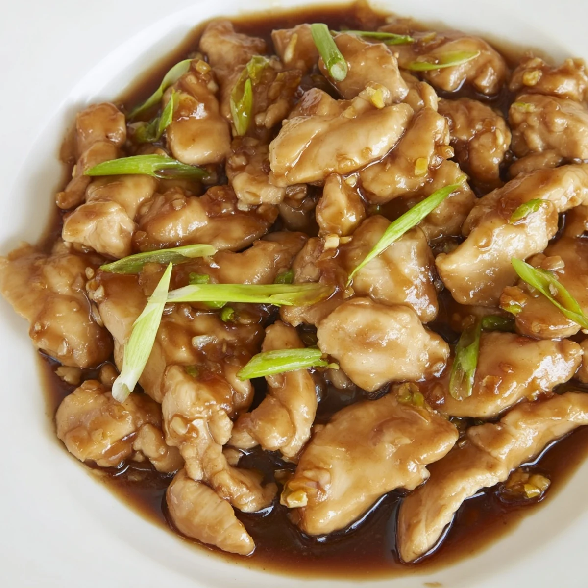 Golden Mongolian chicken pieces coated in rich brown garlic ginger sauce and topped with fresh green scallions