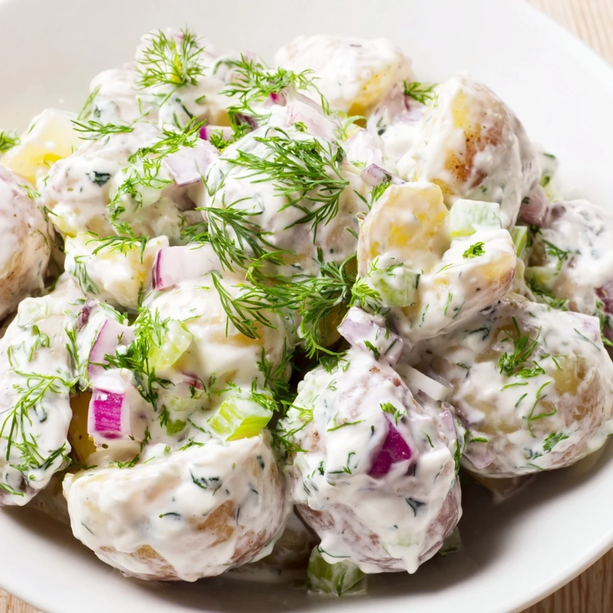 Healthy Greek yogurt potato salad plated for summer picnics with chopped herbs and crisp celery