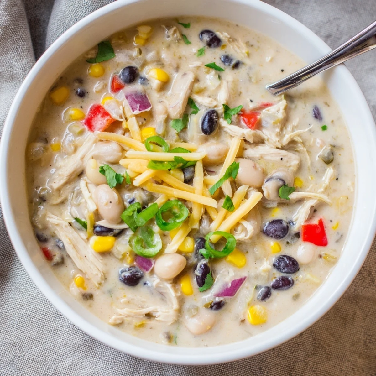 Creamy white chicken chili simmering in a pot with colorful peppers and beans