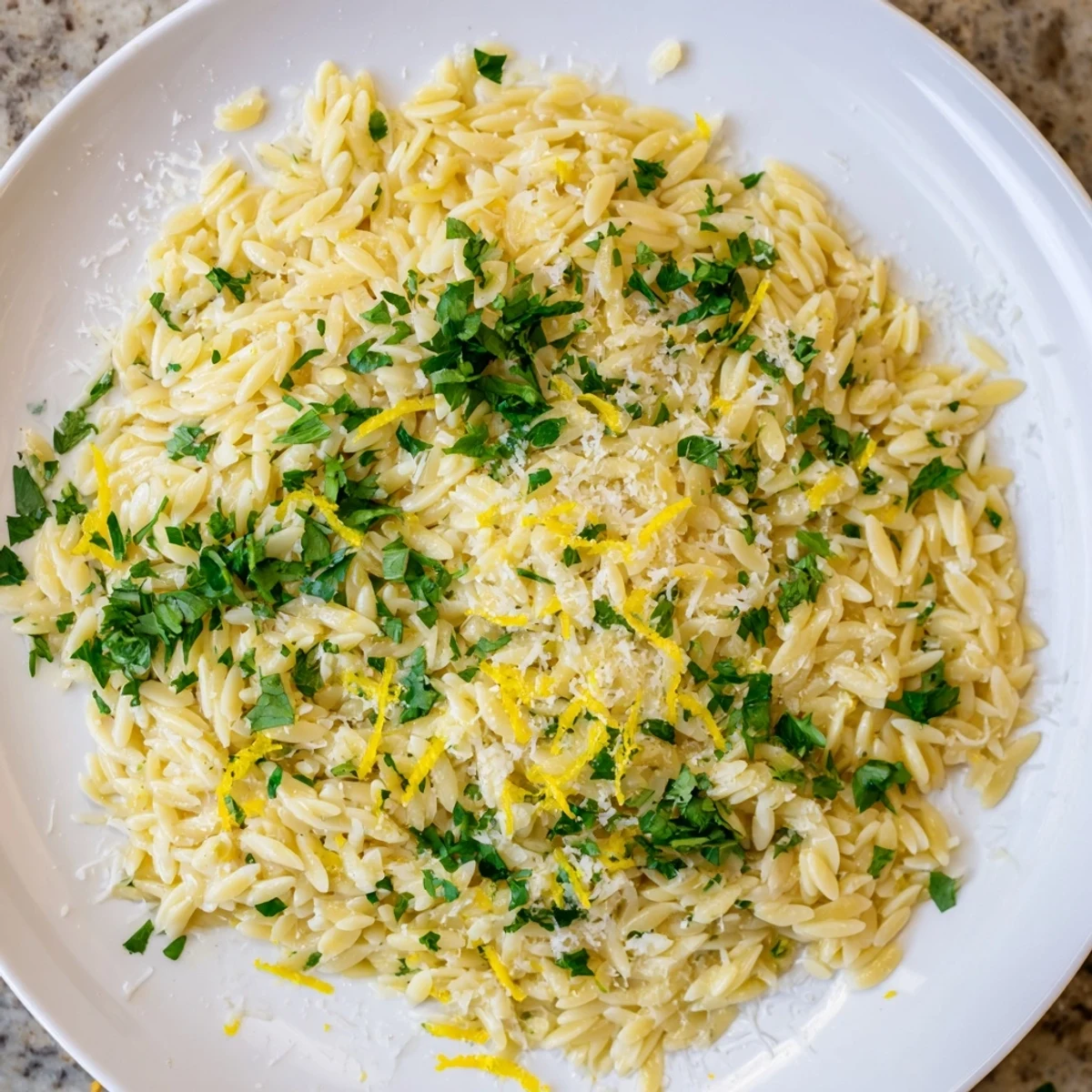 Creamy Mediterranean lemon orzo with bright zest and tender pasta grains on a rustic wooden table