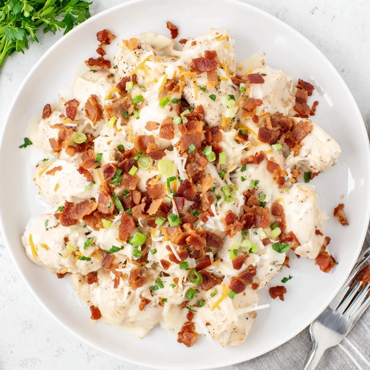 Creamy Crockpot Million Dollar Chicken topped with crispy bacon and melted mozzarella cheese