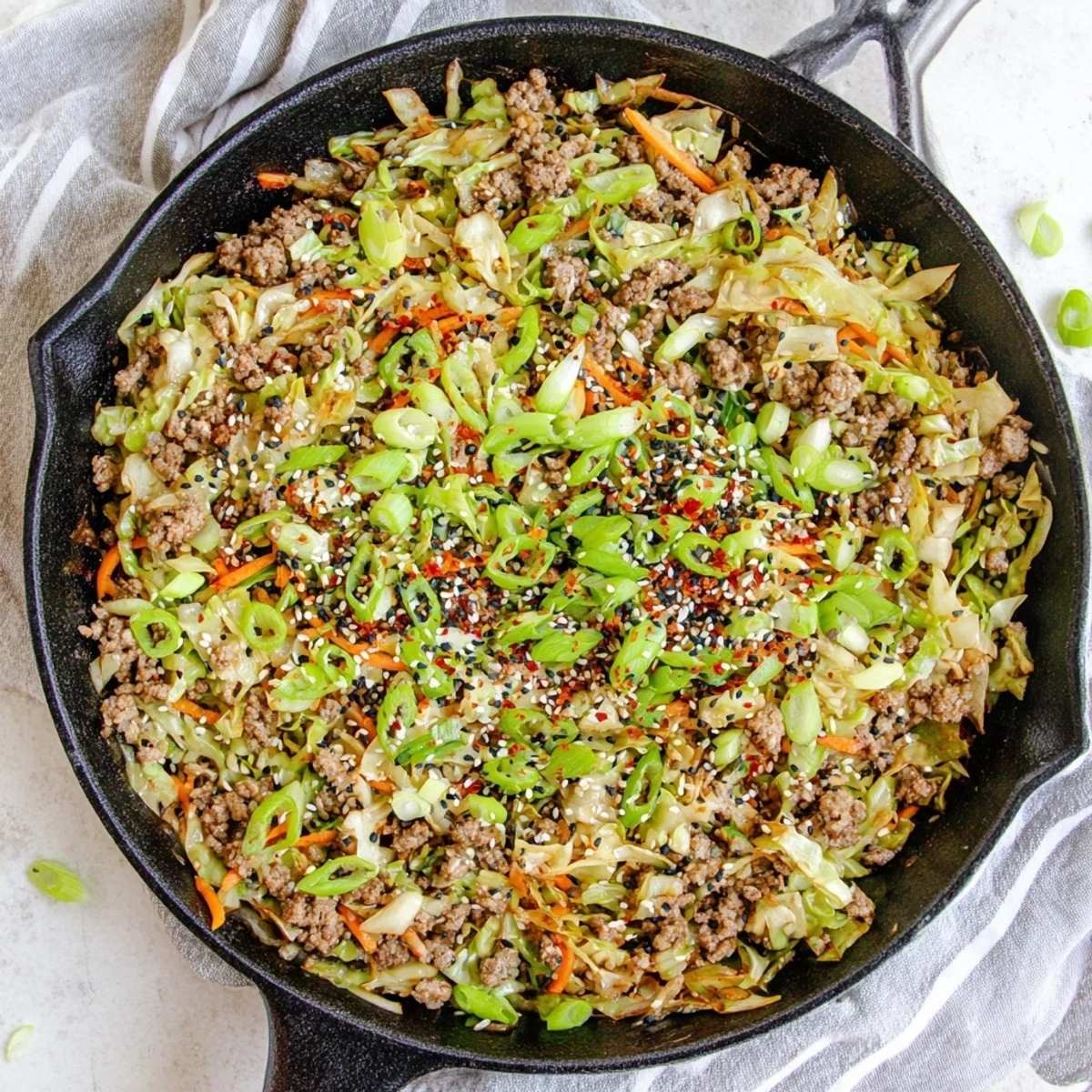 One skillet egg roll in a bowl featuring shredded carrots green onions and sesame seed garnish
