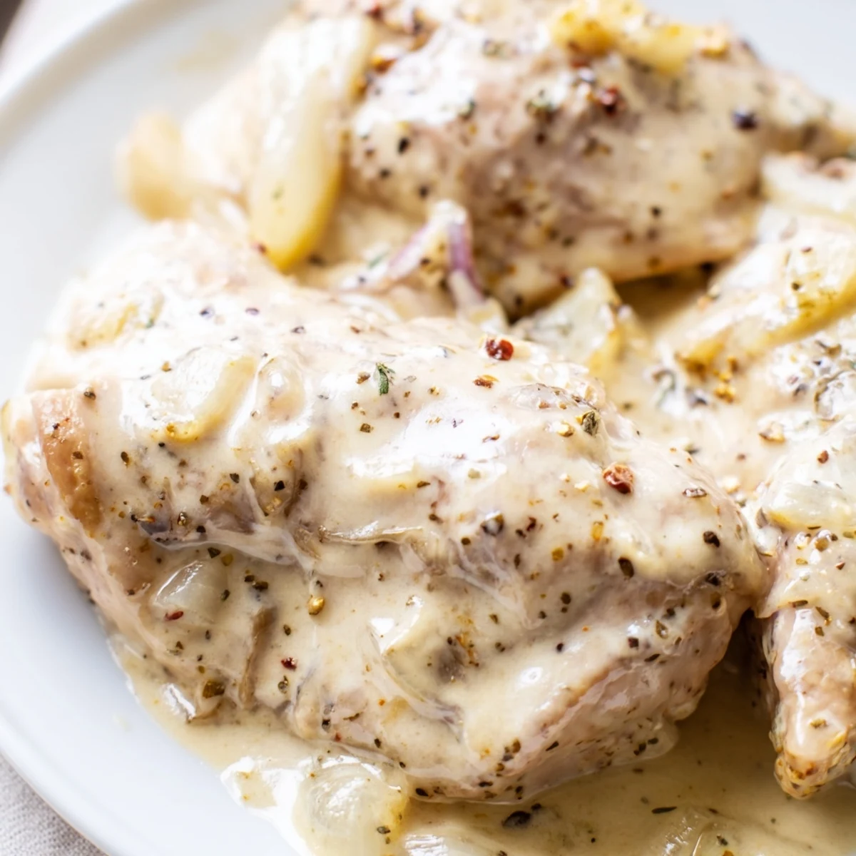 Golden brown chicken thighs swimming in a rich, velvety creamy crockpot gravy sauce