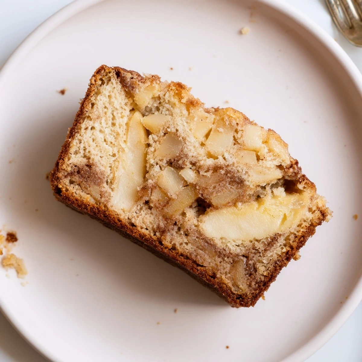 Golden brown cinnamon apple bread loaf with visible apple chunks and cinnamon sugar swirl top