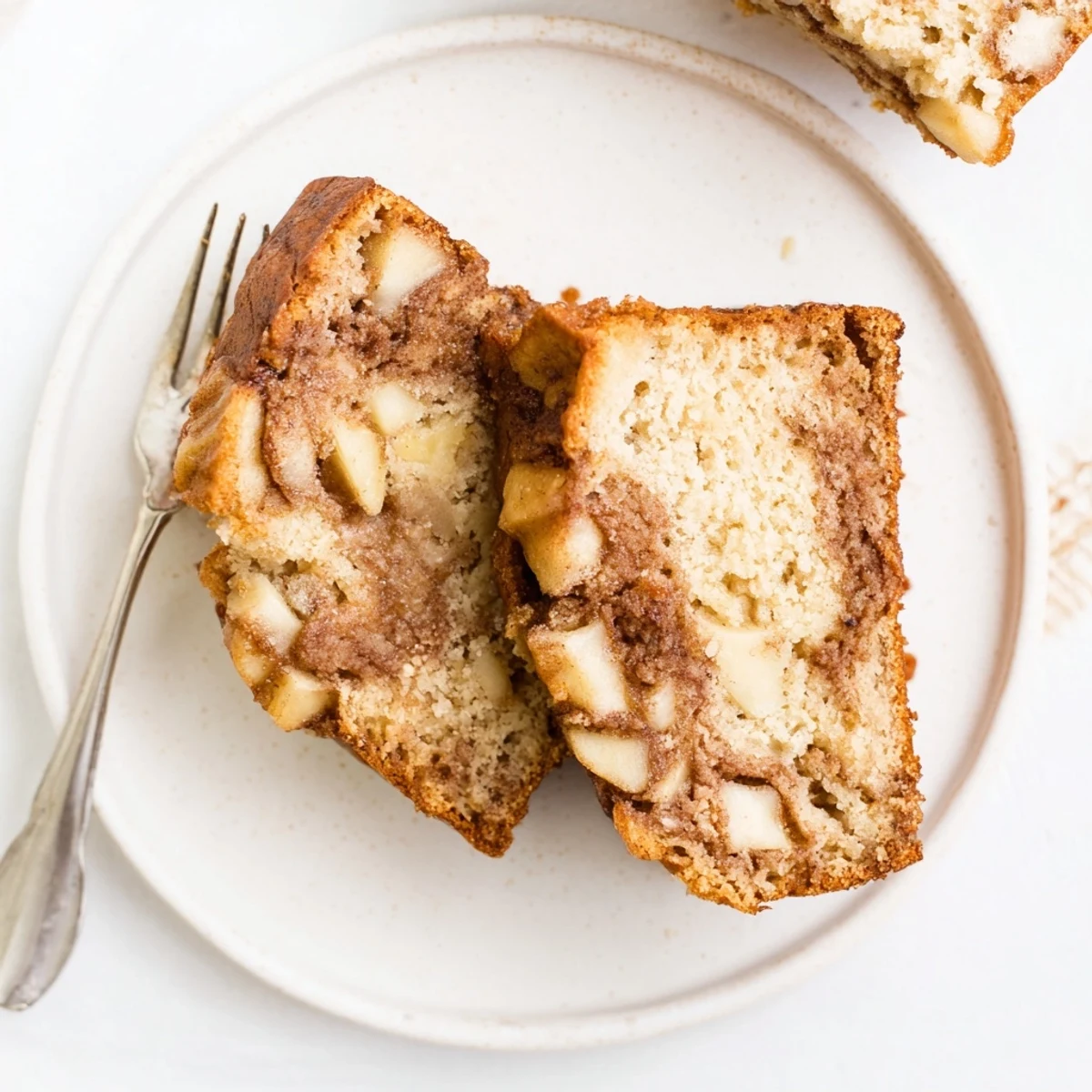 Sliced cinnamon apple bread revealing moist texture and diced apple pieces throughout