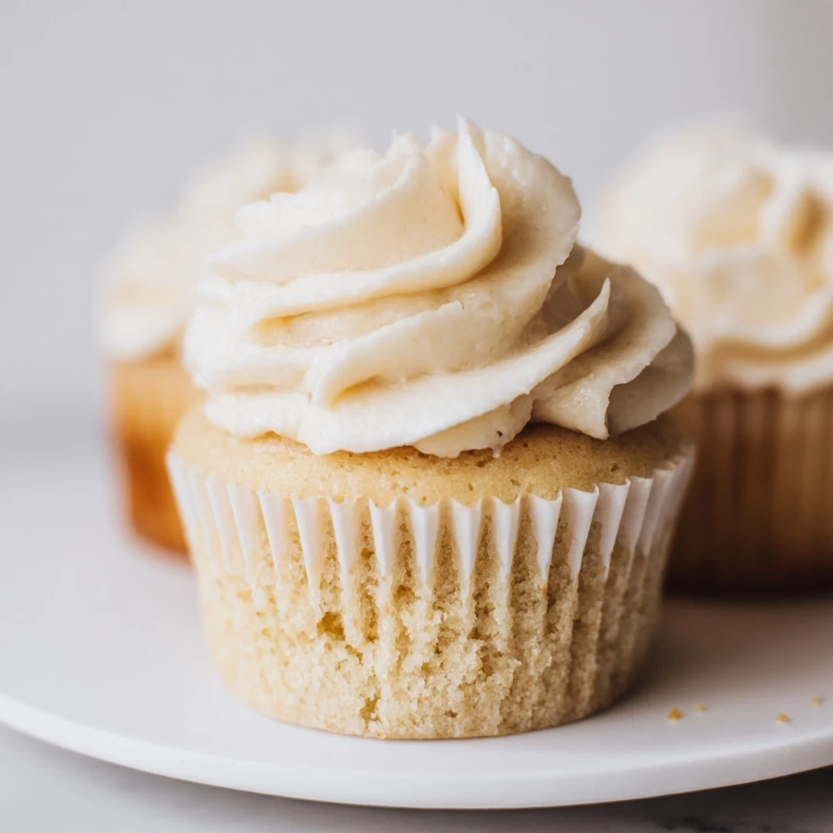 Golden homemade vanilla cupcakes with piped white frosting and colorful sprinkles for celebrations