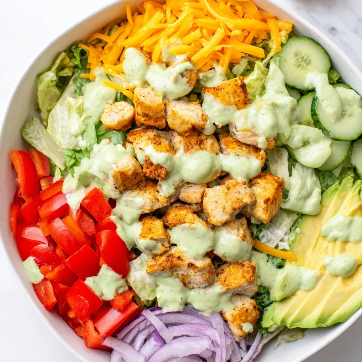 Colorful keto bowls loaded with fresh vegetables, tender spiced chicken, and creamy avocado dressing drizzled on top