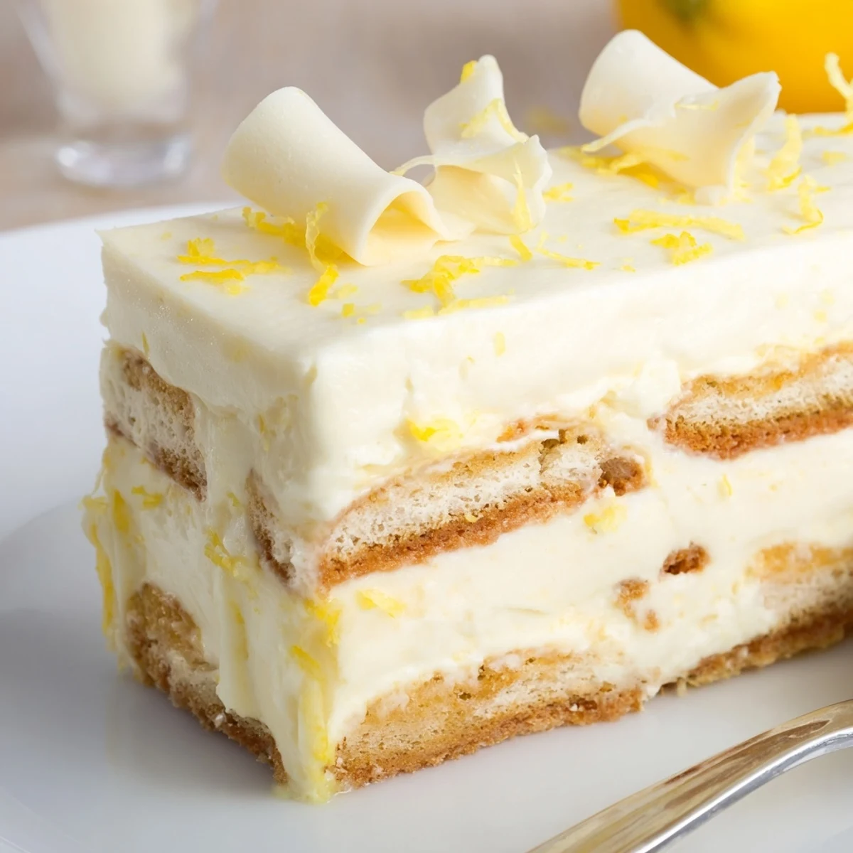 Chilled lemon tiramisu topped with white chocolate curls on a summer dessert plate.