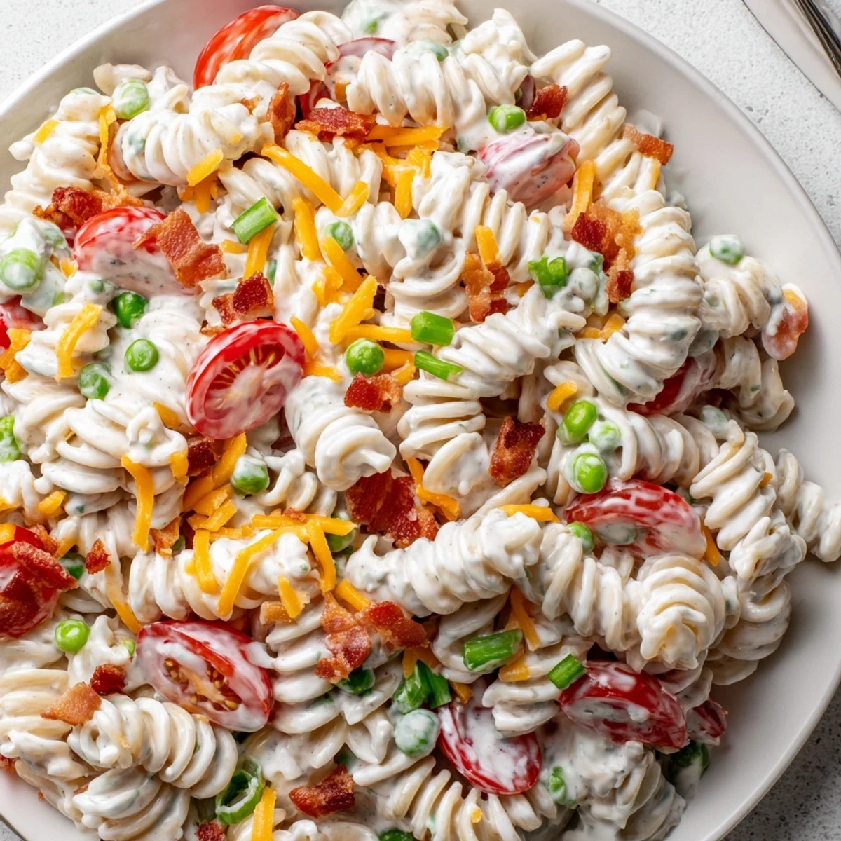 Colorful addictive crack pasta salad mounded in a bowl with cherry tomatoes and crispy bacon bits