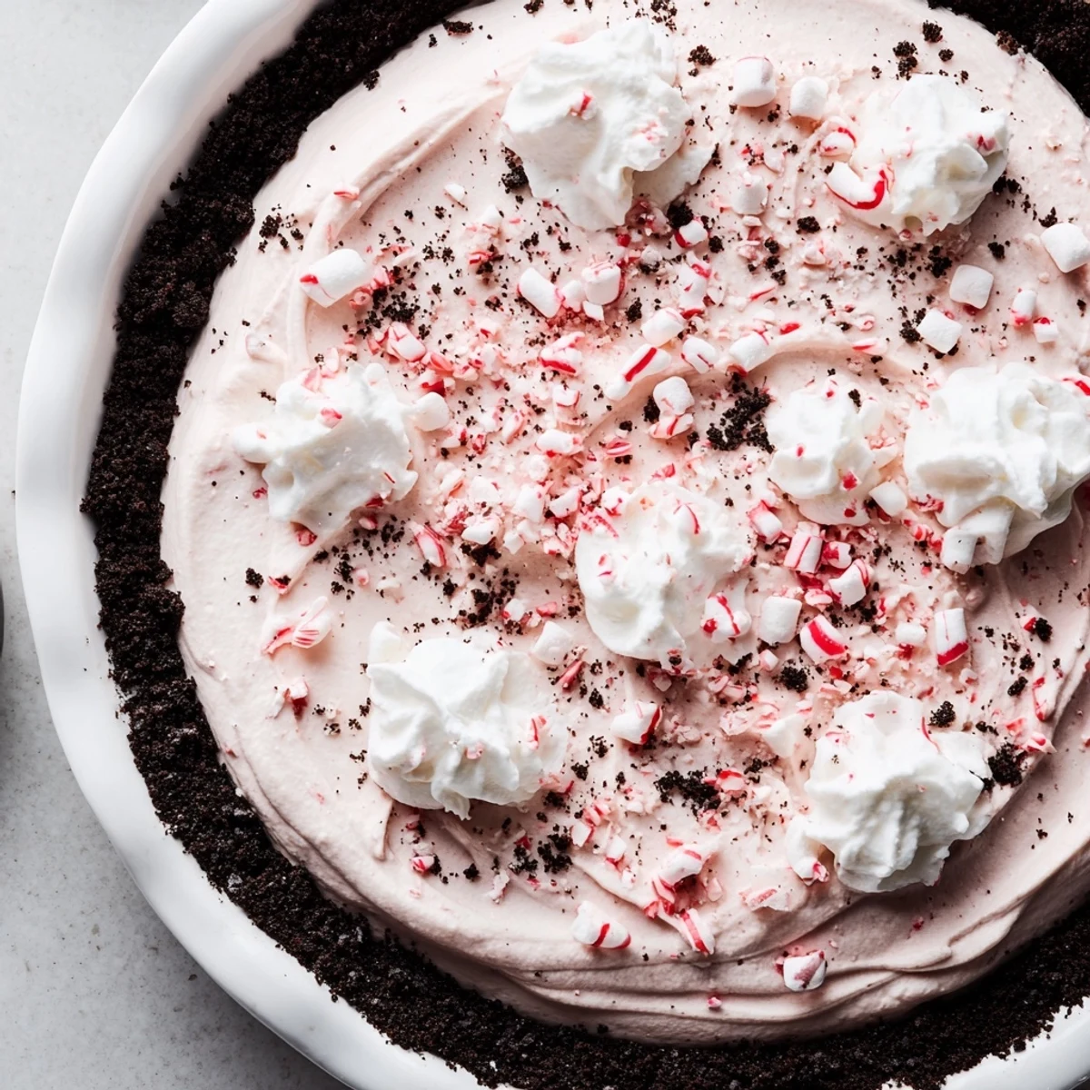 Slice of Candy Cane Pie topped with whipped cream and crunchy peppermint