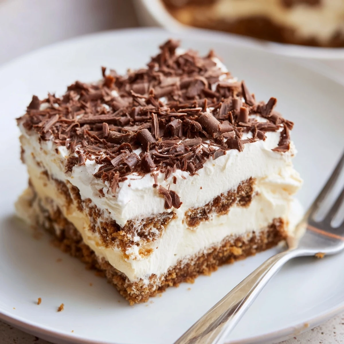 No Bake Layered Dessert with creamy vanilla pudding, whipped cream, and chocolate shavings