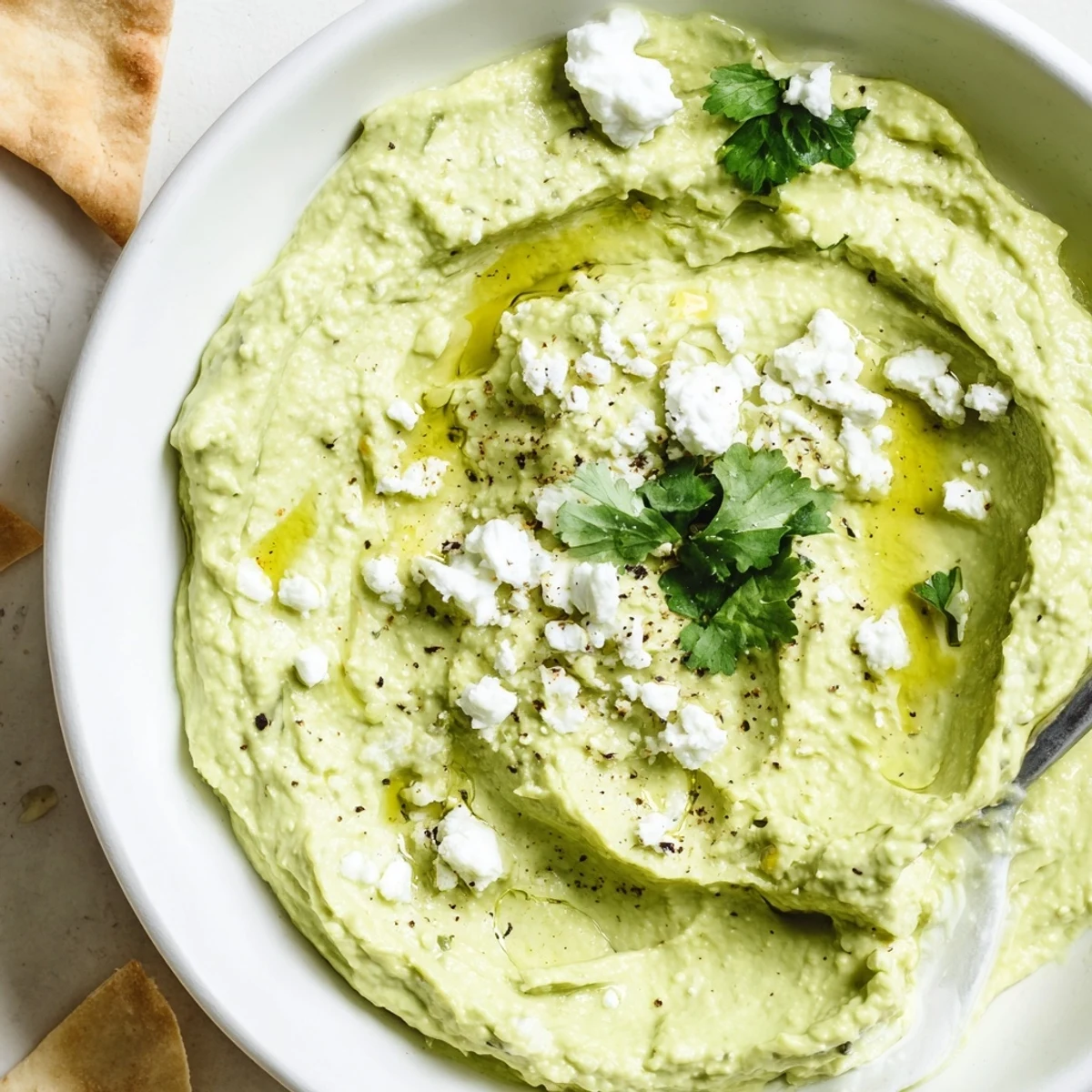 Party ready Creamy Avocado Feta Dip served with pita chips and cilantro