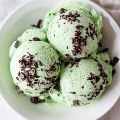 Close-up of creamy, naturally green mint ice cream with dark chocolate chunks melting on top, perfect for summer dessert presentations.  